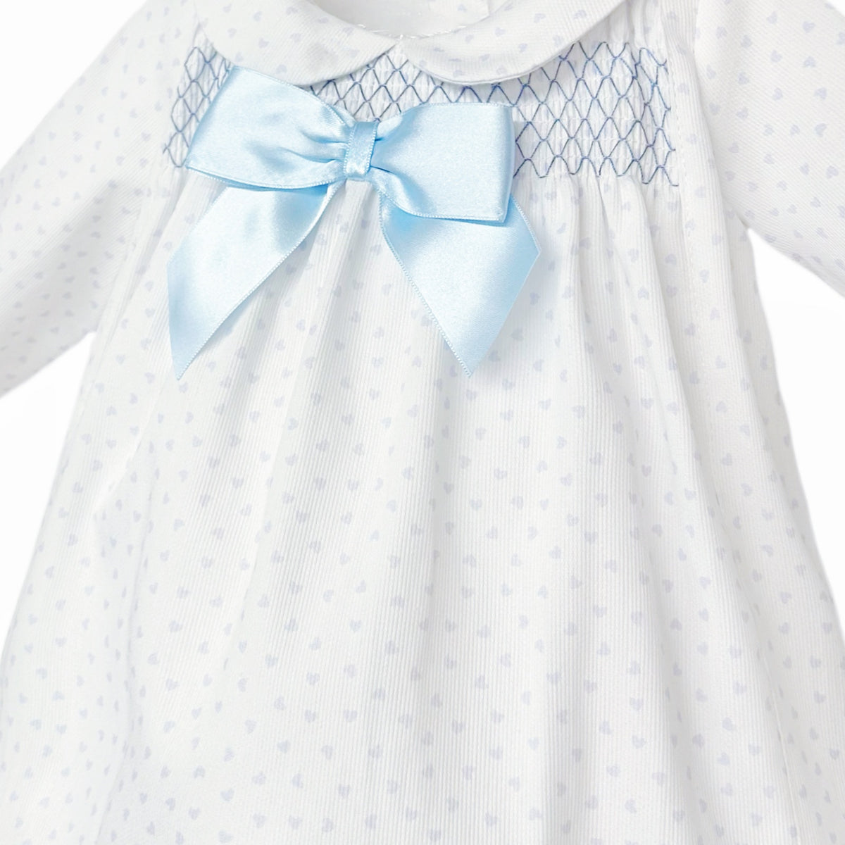 Close-up of blue chest smocking, satin-look bow and tiny blue heart print