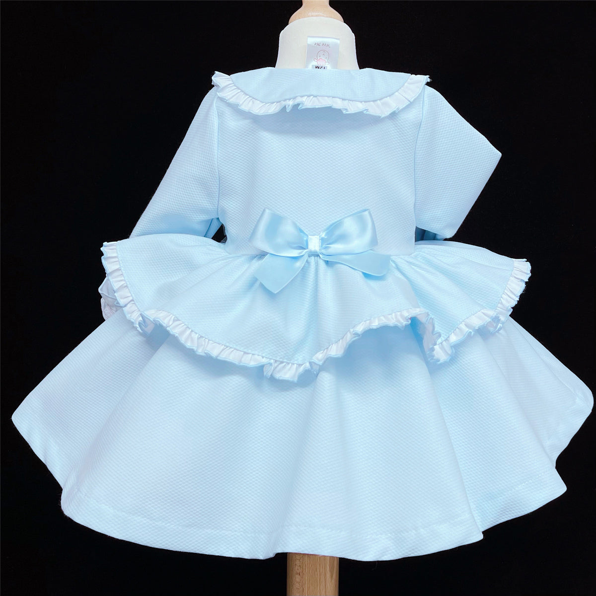 Back of the pale blue jacket with a bow and curved frill-trimmed panel