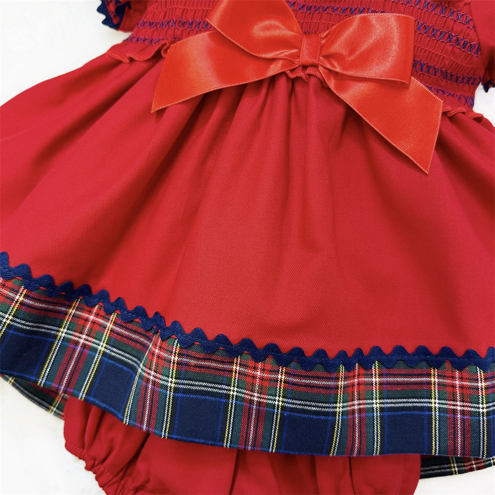 Angled detail of the red dress, bow, tartan skirt border and matching pants
